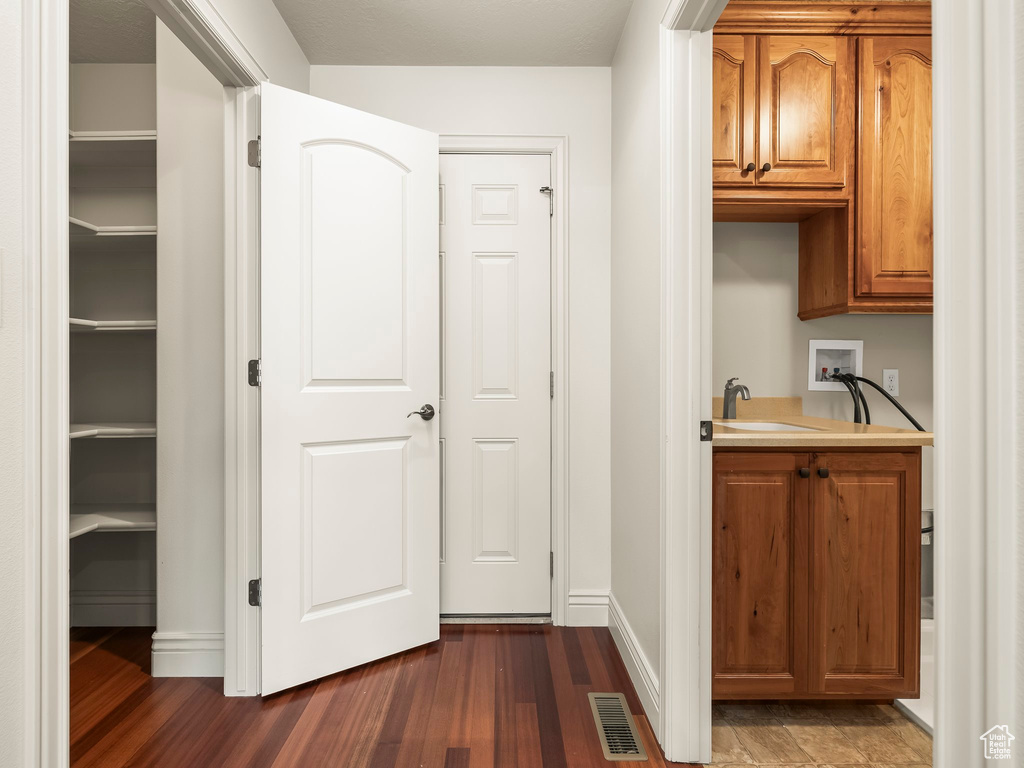 Hallway featuring dark wood finished floors and a sink
