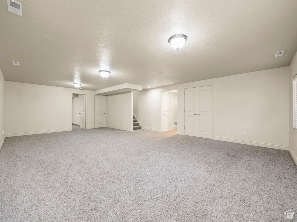 Finished below grade area featuring stairway and light carpet