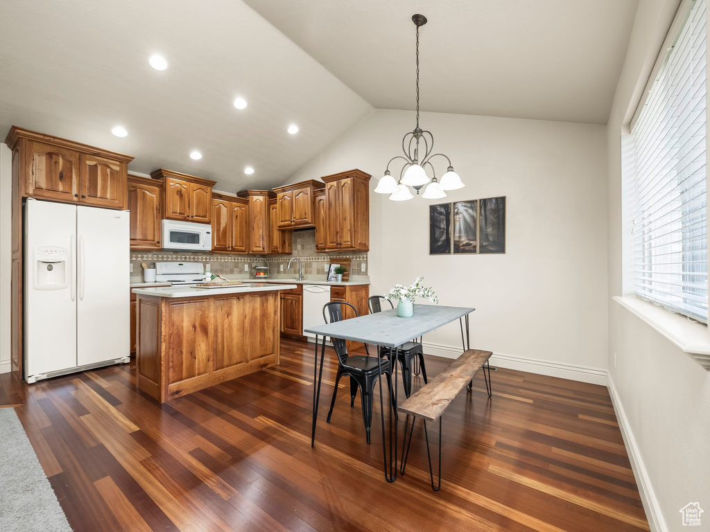 Kitchen with white appliances, light countertops, a chandelier, tasteful backsplash, and brown cabinets
