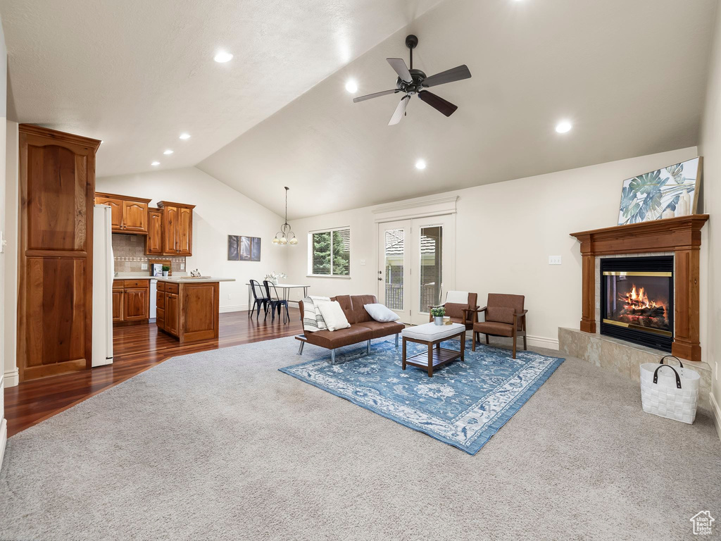 Living room with lofted ceiling, a glass covered fireplace, a ceiling fan, recessed lighting, and dark colored carpet