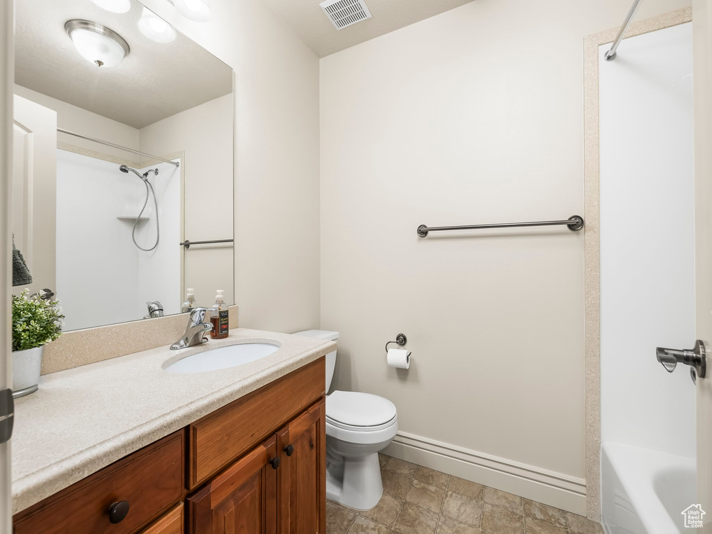 Full bathroom with vanity, stone finish flooring, and washtub / shower combination