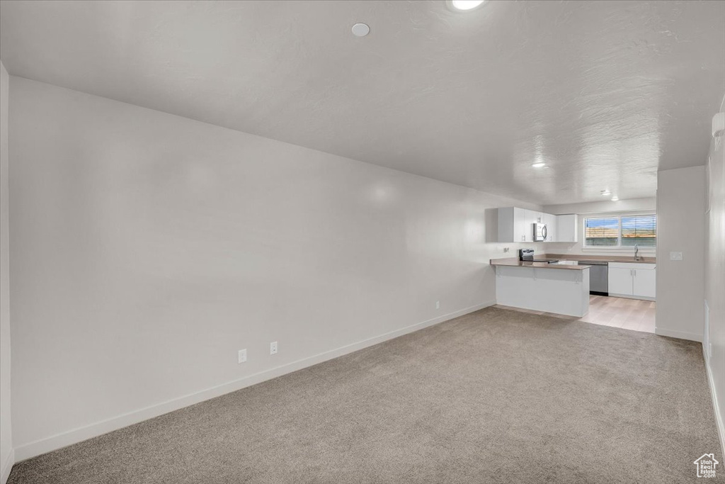 Unfurnished living room with light carpet and baseboards