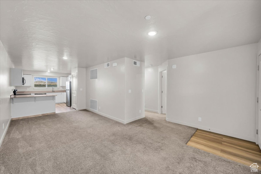 Unfurnished living room featuring light colored carpet and recessed lighting