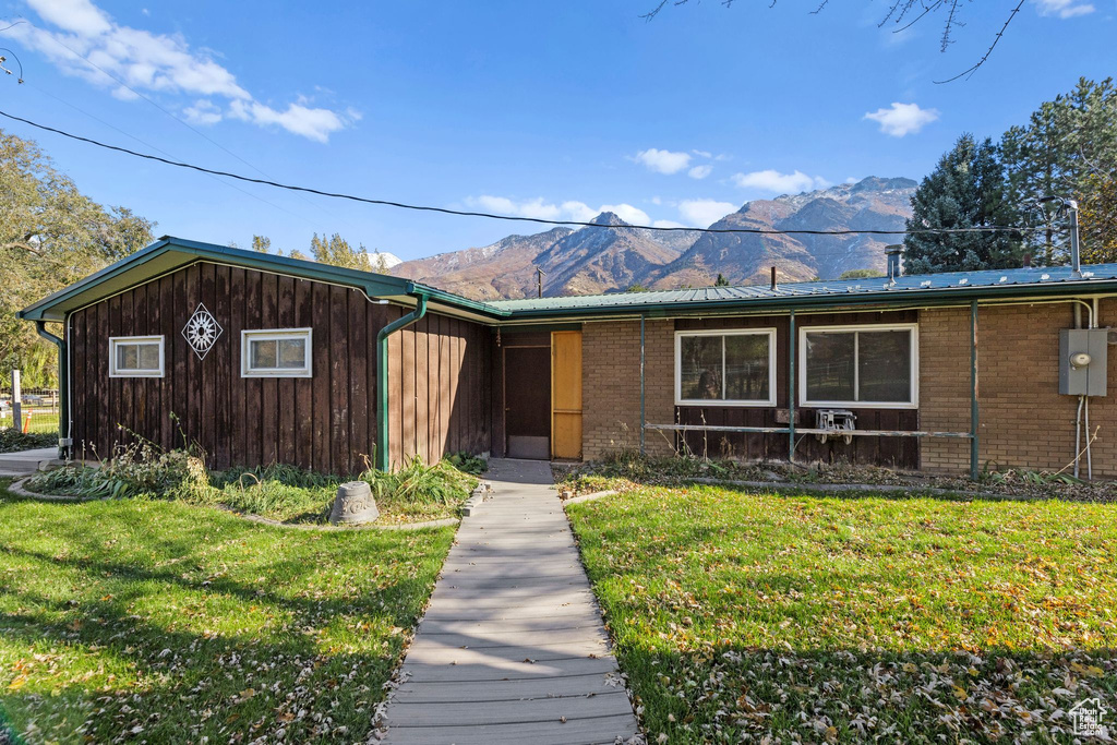 View of front of property featuring a mountain view, a front yard, and brick siding