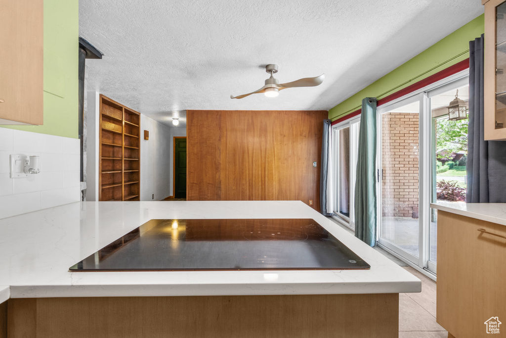 Kitchen with a textured ceiling, ceiling fan, light countertops, and light tile patterned floors