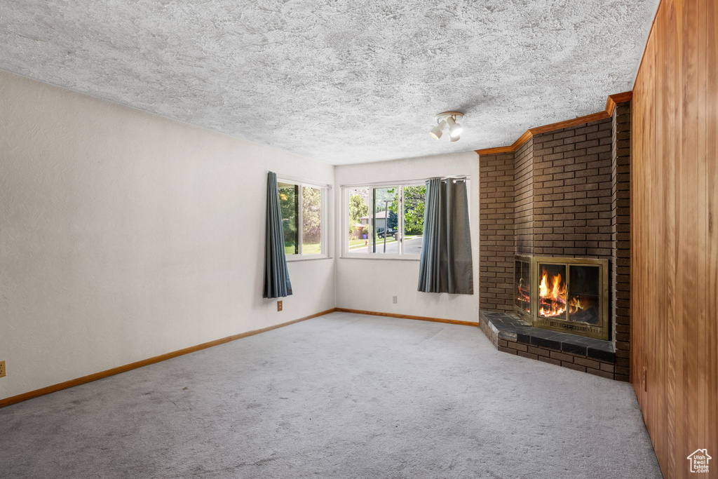 Unfurnished living room with carpet floors, a fireplace, and a textured ceiling
