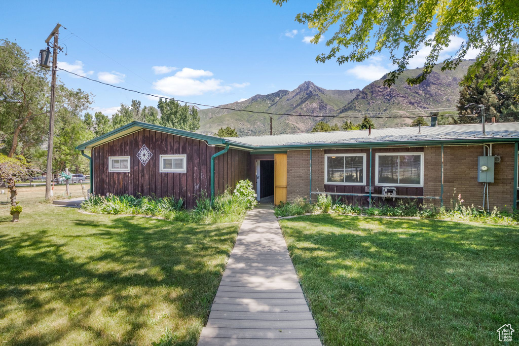 View of front facade with a mountain view, a front lawn, and brick siding
