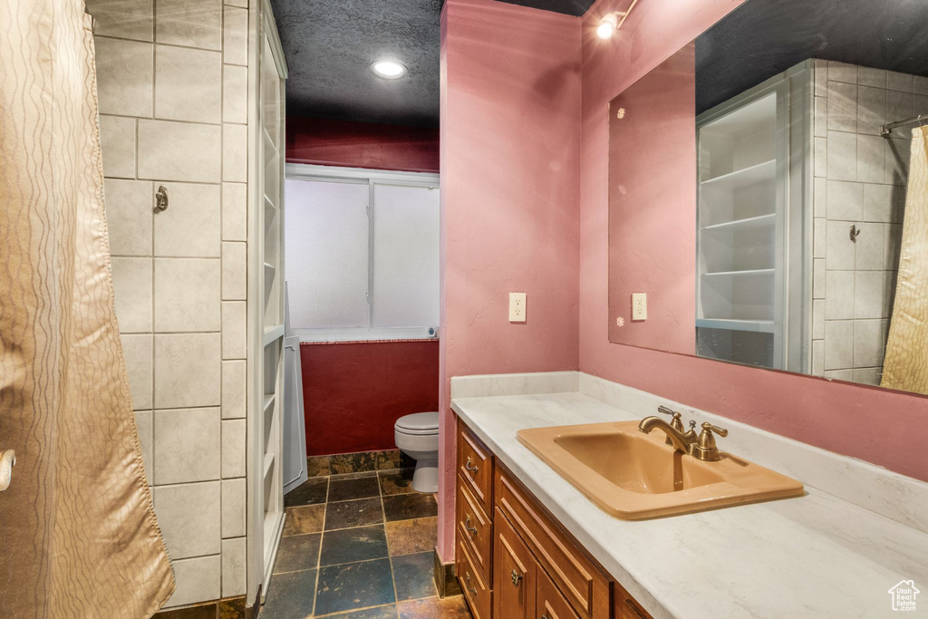 Bathroom featuring stone tile flooring, vanity, curtained shower, and recessed lighting