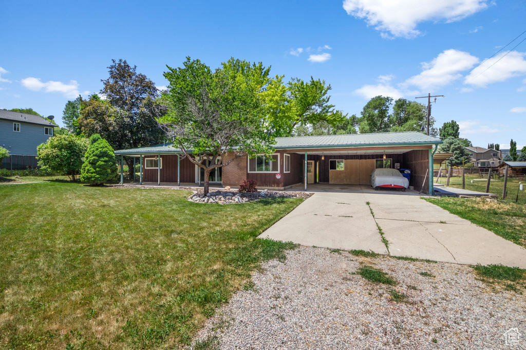 Back of house with driveway, an attached carport, and a metal roof