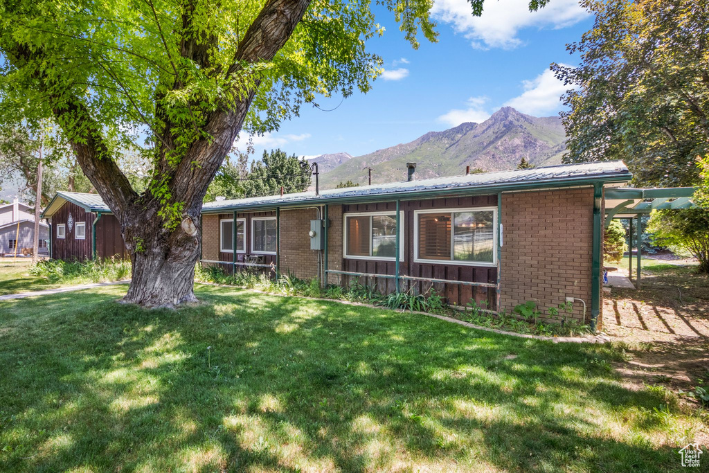 Single story home featuring brick siding, a mountain view, and a front lawn