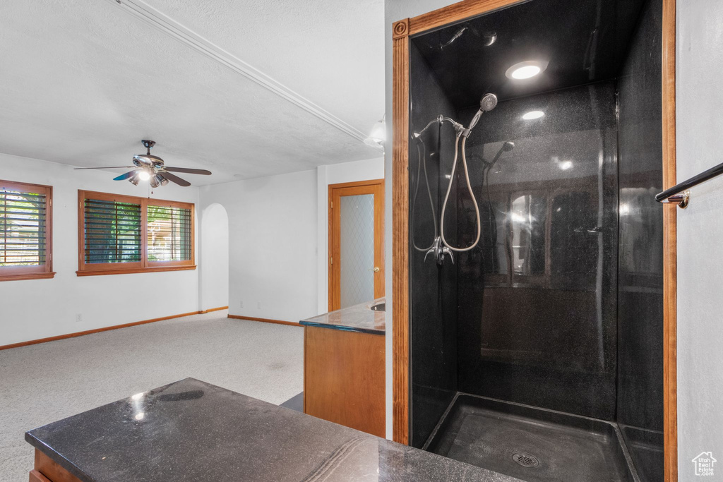 Bathroom featuring tiled shower, vanity, and ceiling fan