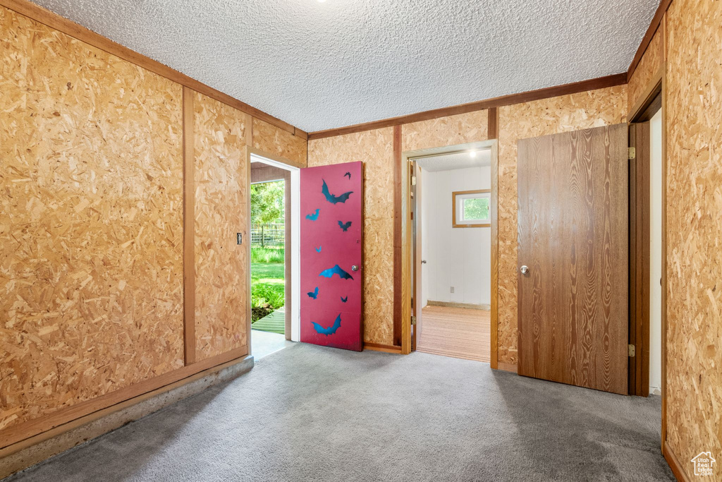 Carpeted empty room with a textured ceiling and ornamental molding