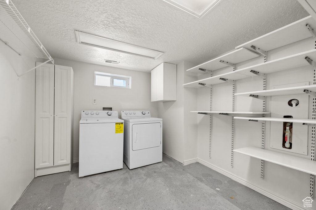 Washroom featuring independent washer and dryer and a textured ceiling
