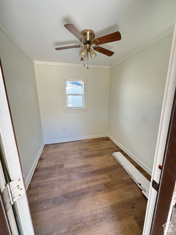 Spare room with ornamental molding, wood finished floors, and a ceiling fan