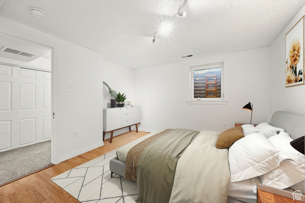 Bedroom featuring light wood-type flooring, track lighting, and a textured ceiling