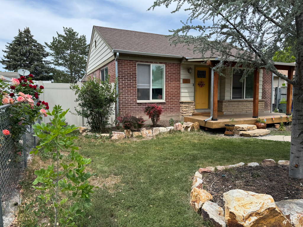 View of front of house with covered porch, brick siding, and a shingled roof