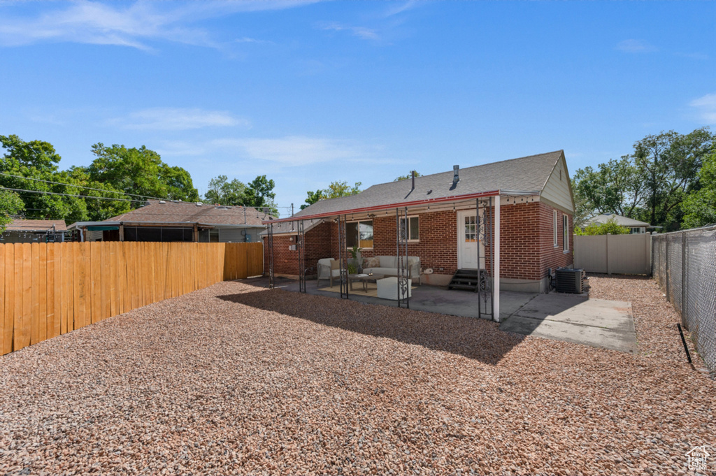 Rear view of house with entry steps, a patio area, brick siding, a fenced backyard, and roof with shingles