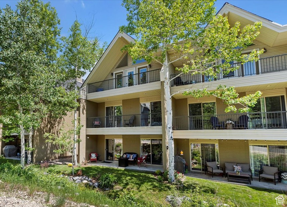 Rear view of property with an outdoor living space, a patio area, and a balcony
