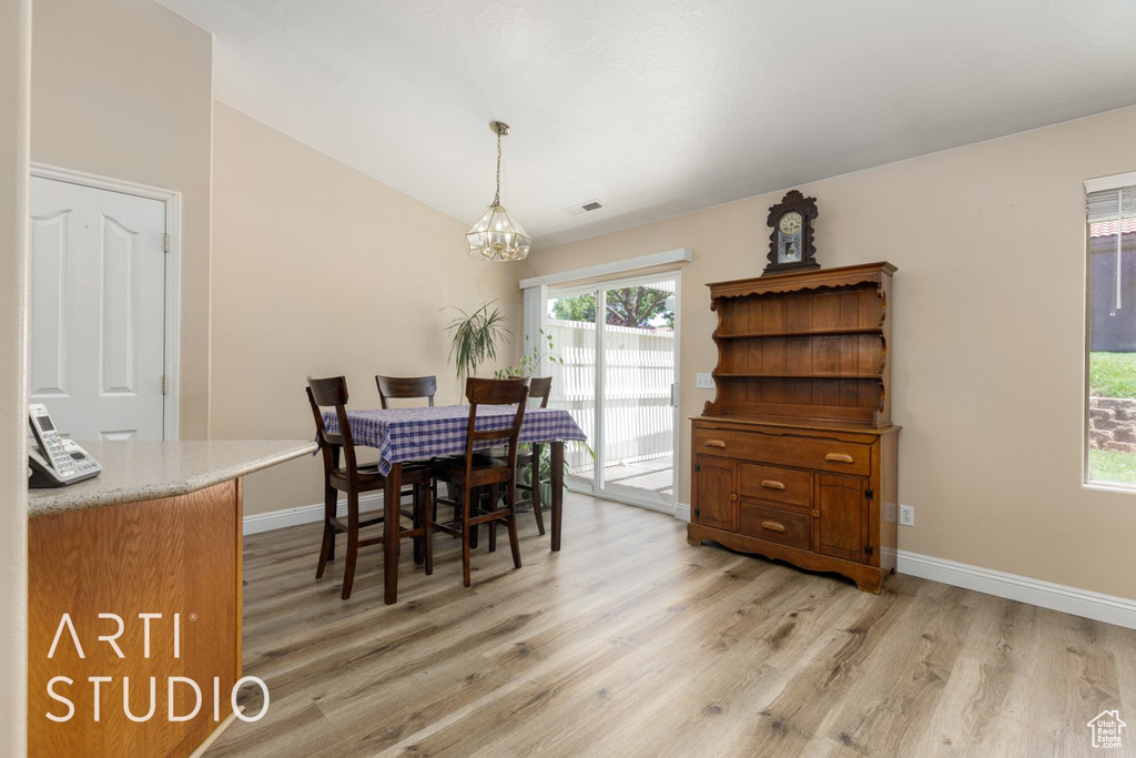 Dining space featuring a chandelier, light wood-style floors, baseboards, and vaulted ceiling