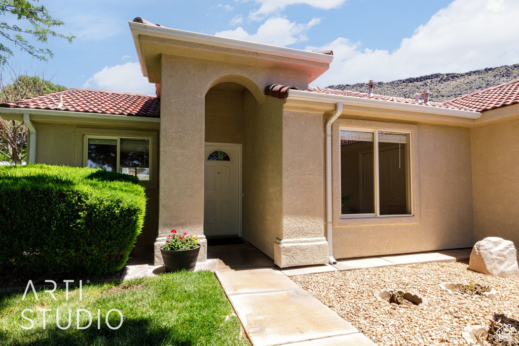 Entrance to property with stucco siding, a tile roof, and a mountain view