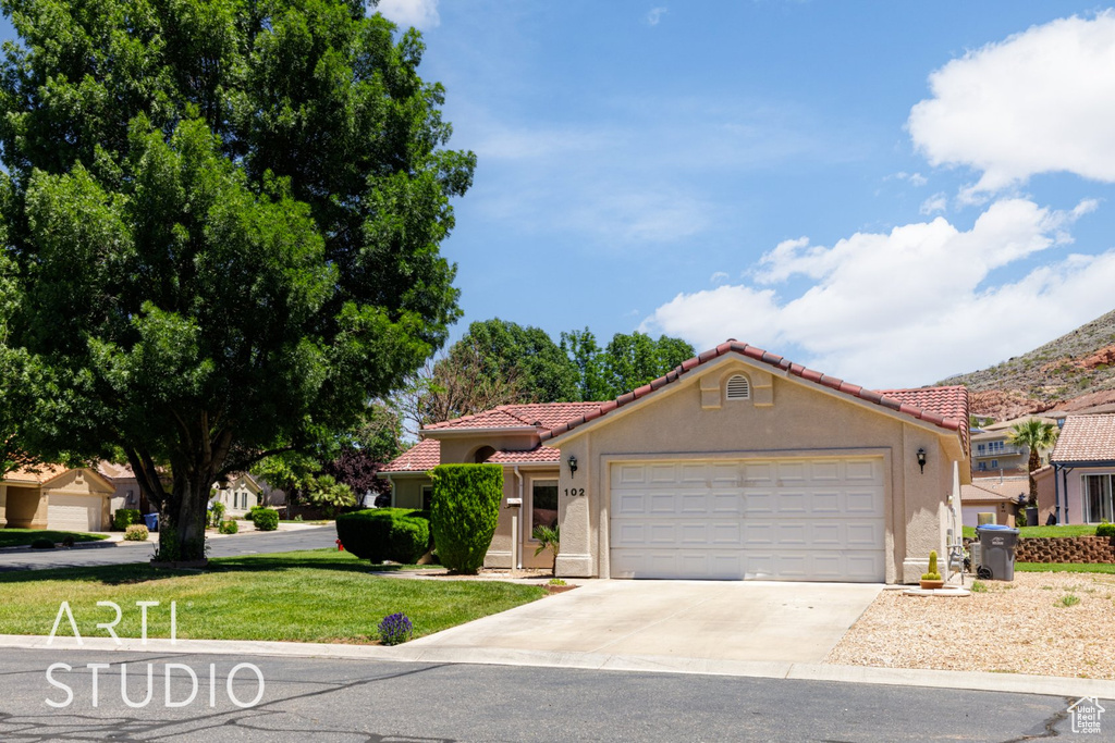 Mediterranean / spanish-style house featuring a tile roof, concrete driveway, an attached garage, and stucco siding