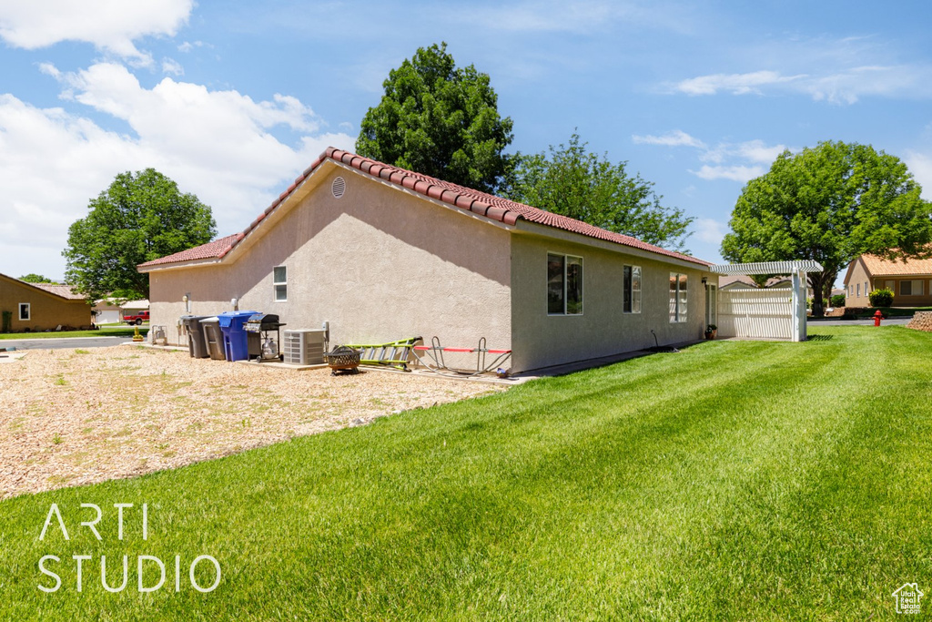 Rear view of property featuring a yard, stucco siding, and a tiled roof