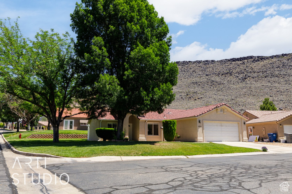 Ranch-style home featuring a garage, stucco siding, concrete driveway, and a front yard