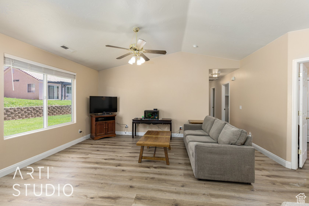 Living room featuring light wood finished floors, ceiling fan, vaulted ceiling, and baseboards