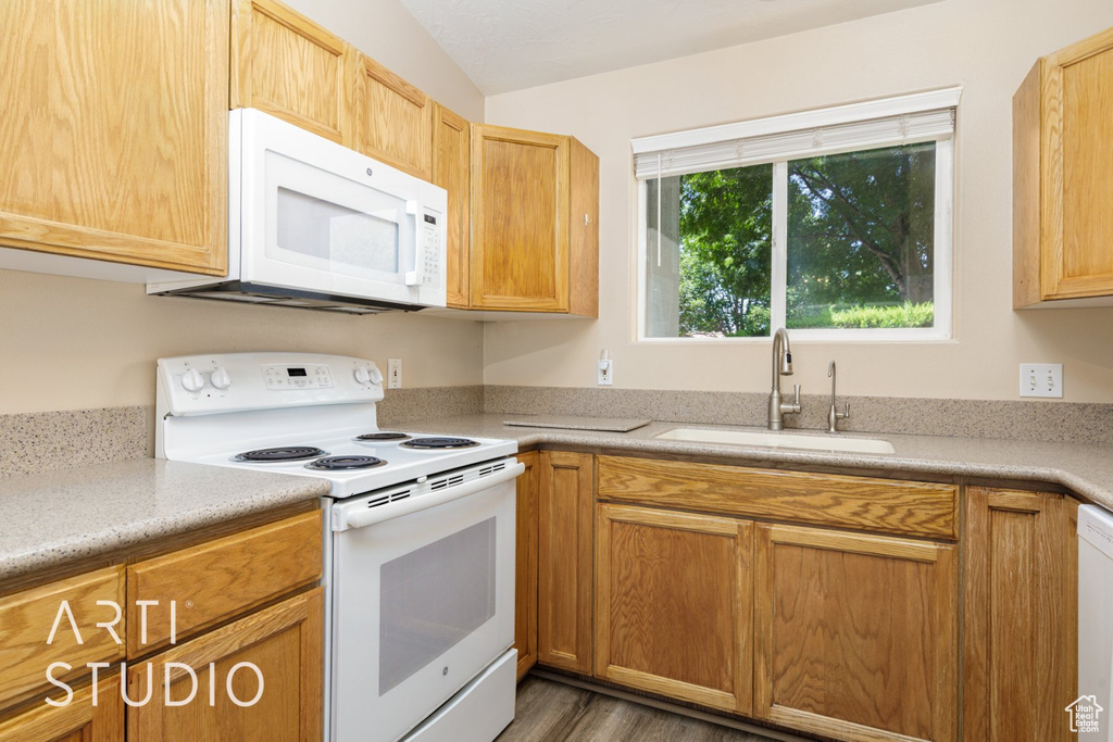 Kitchen featuring white appliances, a sink, light countertops, and wood finished floors