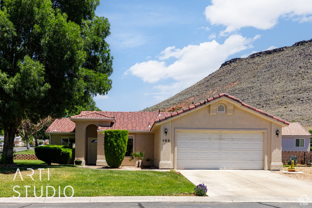 Mediterranean / spanish-style home featuring concrete driveway, stucco siding, an attached garage, a front lawn, and a tile roof