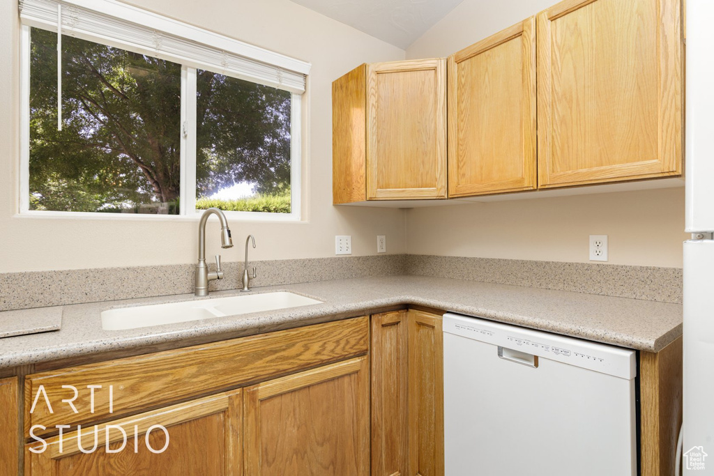 Kitchen featuring white dishwasher, a sink, light countertops, and light brown cabinetry