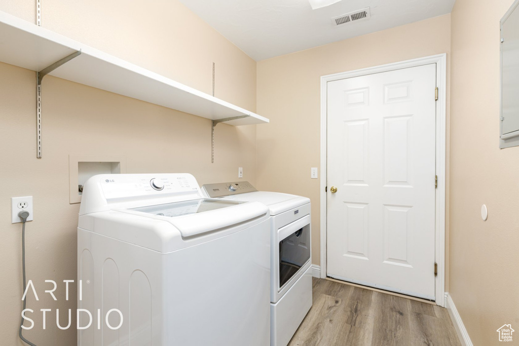 Washroom with independent washer and dryer, light wood-style floors, and baseboards