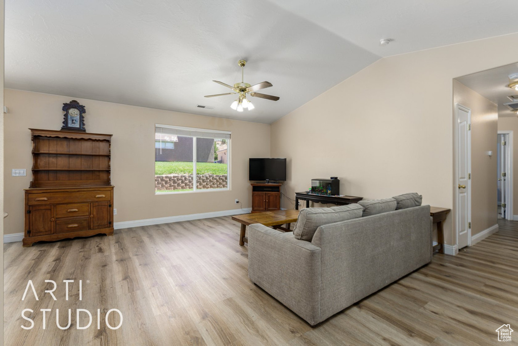 Living area with a ceiling fan, light wood-style floors, lofted ceiling, and baseboards