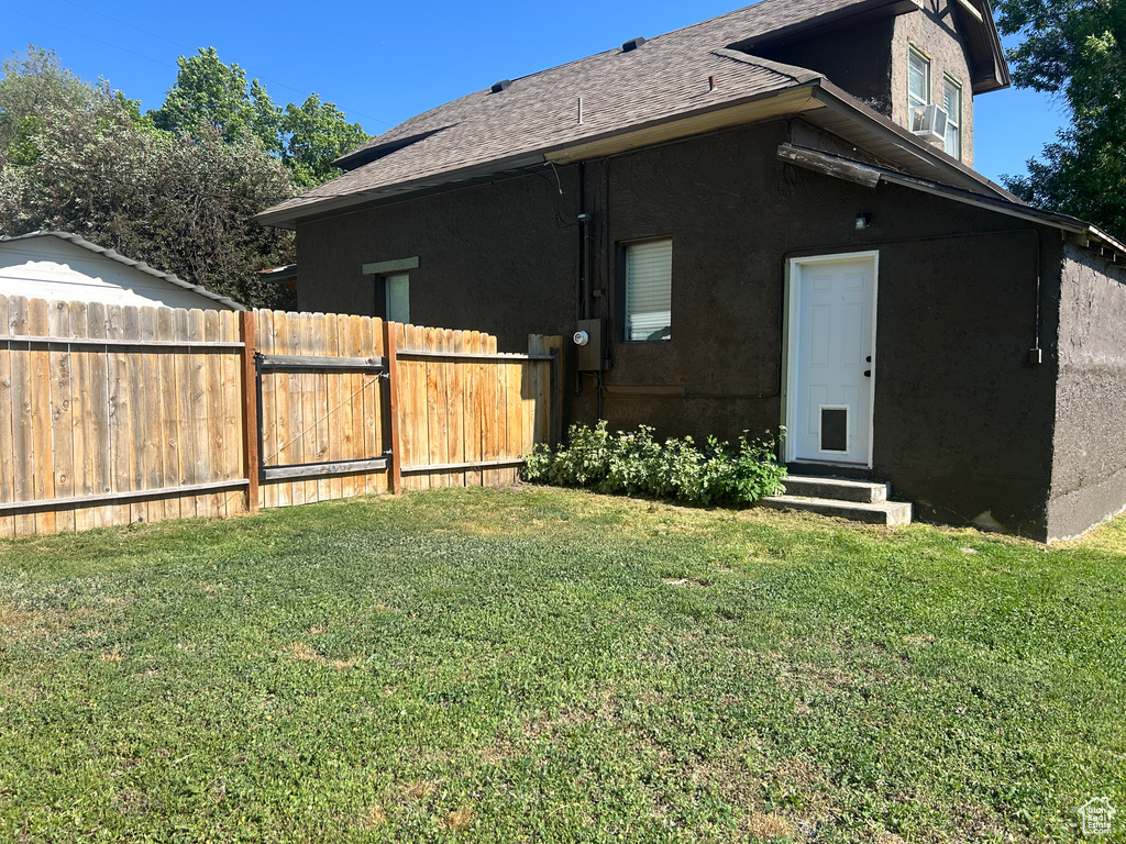 Back of property with entry steps, roof with shingles, and stucco siding