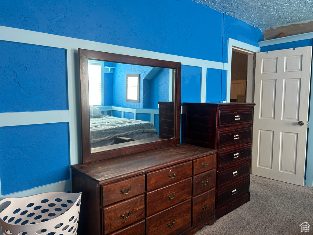 Carpeted bedroom featuring a textured ceiling and a textured wall