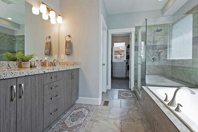 Full bath featuring vanity, a stall shower, a bath, and marble finish flooring