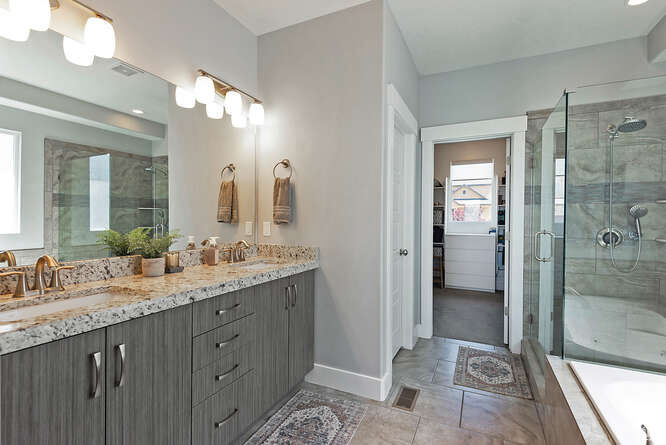 Bathroom featuring double vanity, a shower stall, plenty of natural light, and a spacious closet