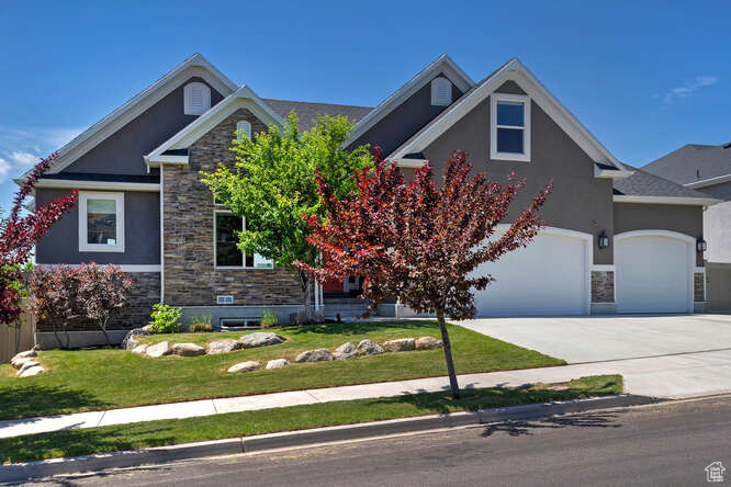 View of front of property featuring stucco siding, stone siding, and a front yard