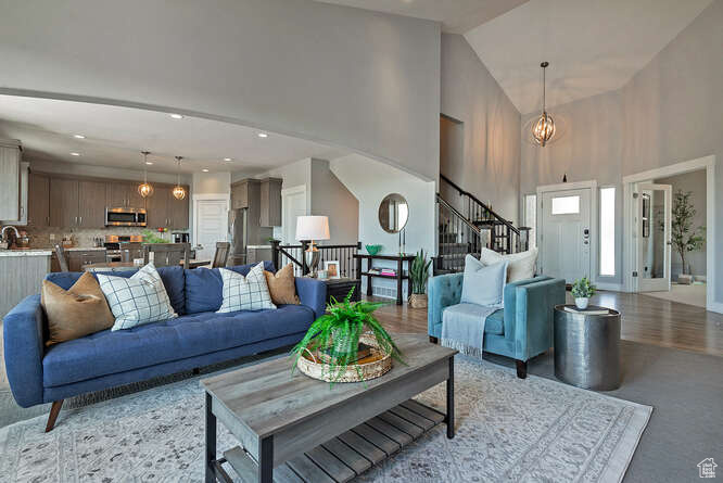 Living room featuring high vaulted ceiling, stairway, recessed lighting, and a chandelier