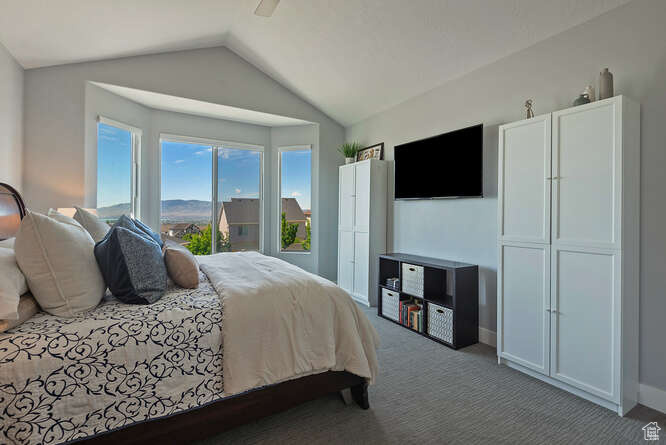 Bedroom featuring carpet, vaulted ceiling, and a ceiling fan