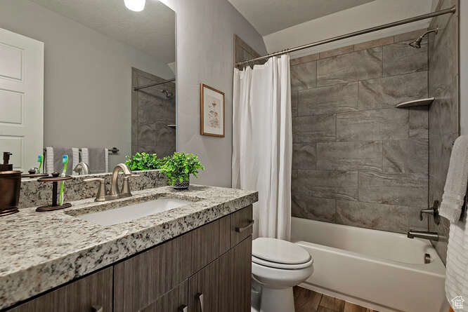 Full bathroom featuring vanity, wood finished floors, and shower / bath combination with curtain