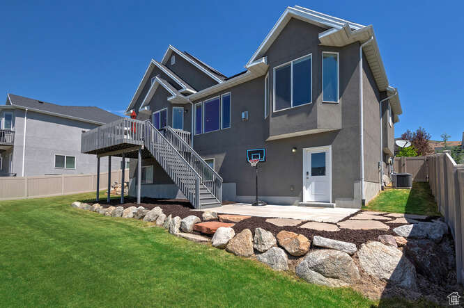 Back of property featuring stairway, a deck, stucco siding, a fenced backyard, and a patio area