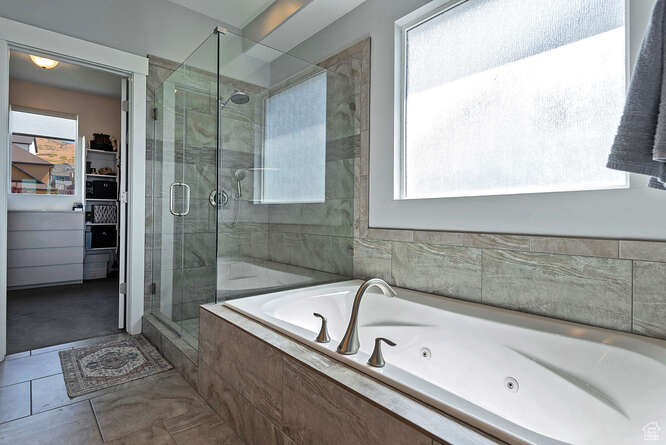Full bathroom with a stall shower, a whirlpool tub, a spacious closet, and tile patterned floors