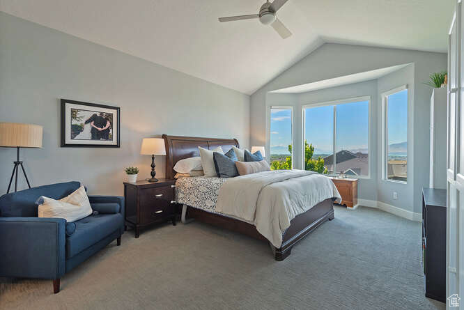 Bedroom featuring light colored carpet, vaulted ceiling, and ceiling fan