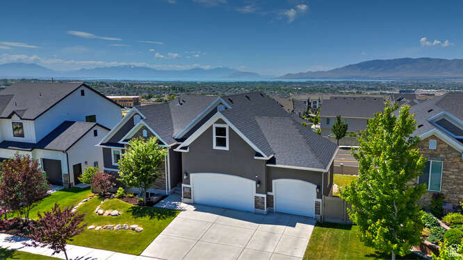 View of front of home featuring an attached garage, driveway, stucco siding, a residential view, and a mountain view