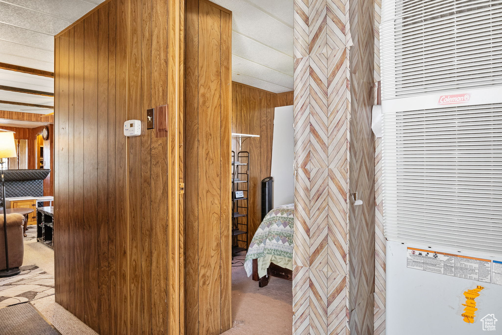 Hall featuring light colored carpet, a heating unit, and wood walls
