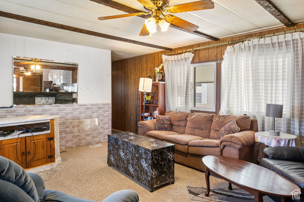 Living room featuring wood walls, ceiling fan, and light colored carpet