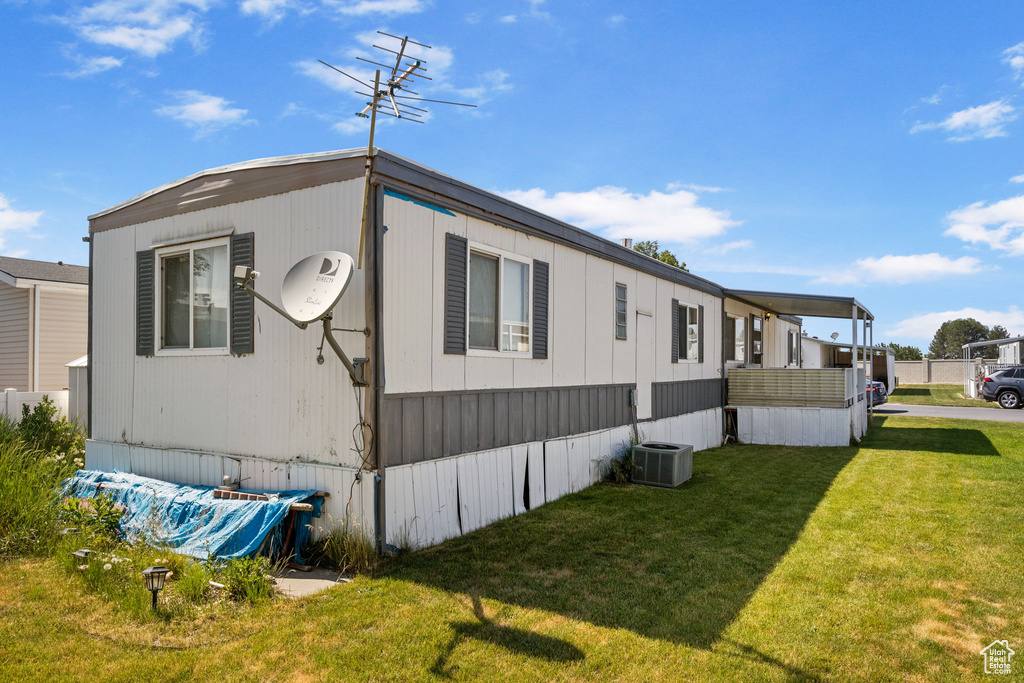 View of side of property with a yard and central AC