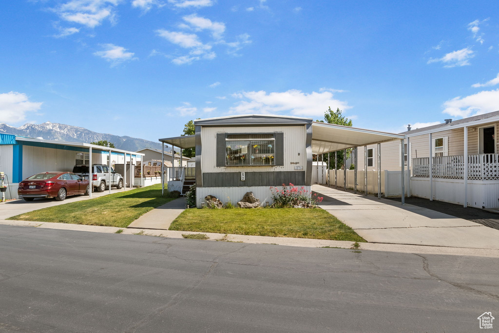 Manufactured / mobile home with an attached carport, a mountain view, and concrete driveway