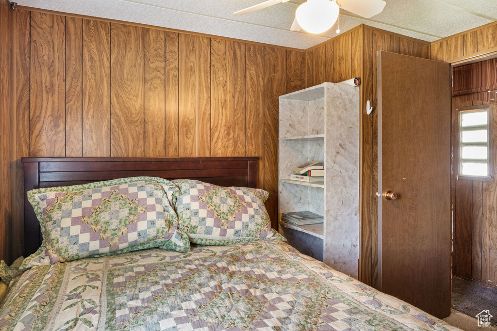 Bedroom with wood walls and ceiling fan